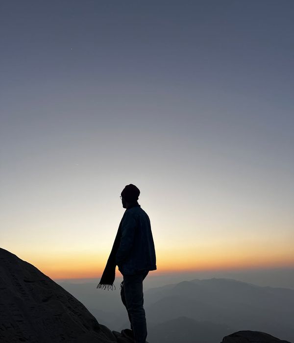 Silhouette of a man stretching against a sunrise.